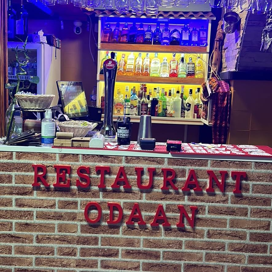 Fachada interior do Restaurant Odaan com letras vermelhas sobre parede de tijolo